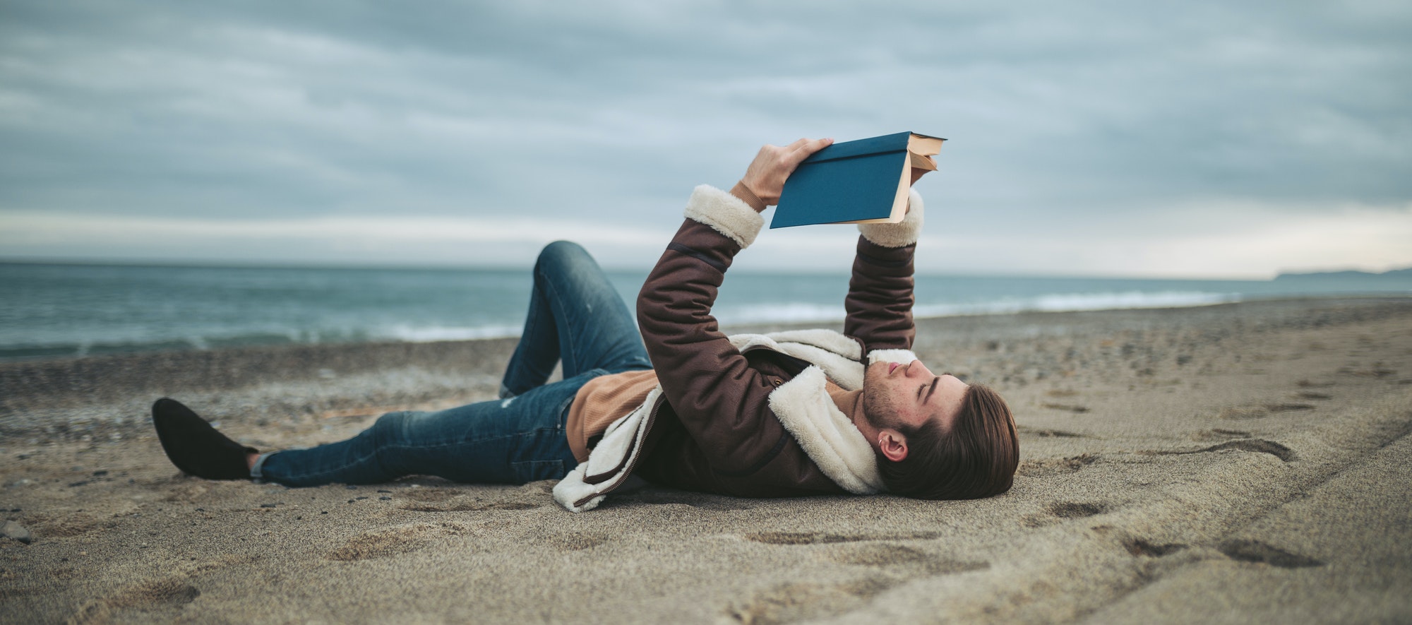 Boy reading book on the beach near the Ocean